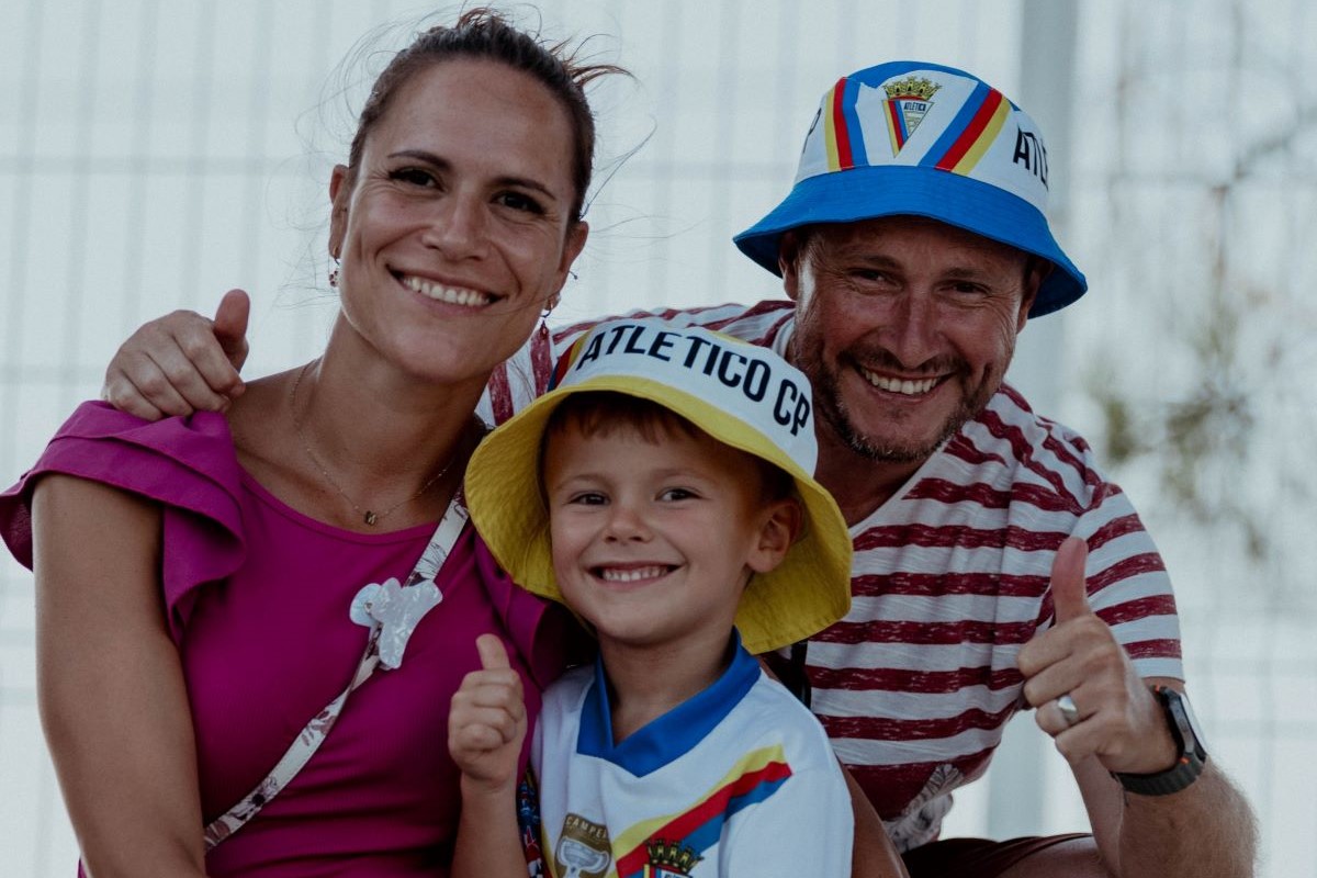 Supporters of Atlético Clube de Portugal wearing club accessories on a match day at Tapadinha Stadium.