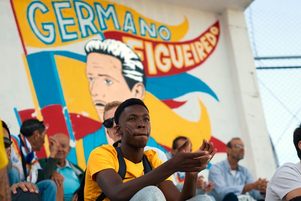Público nas bancadas do Estádio da Tapadinha junto a uma pintura mural dedicada à história do Atlético Clube de Portugal.