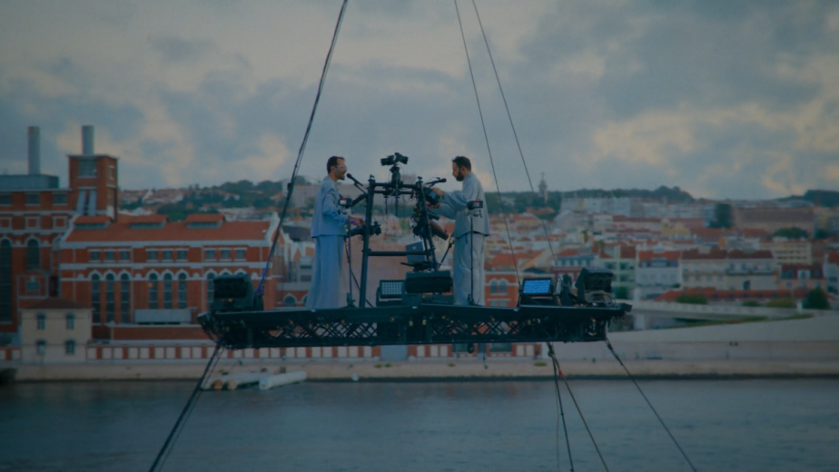 Moulinex and GPU Panic standing on a platform above the Tagus River in Lisbon, with MAAT on the background
