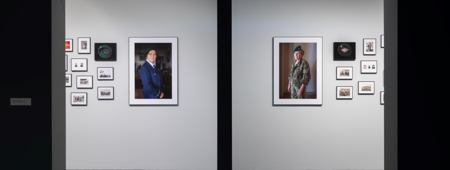 Photographs of women soldiers, hung on the walls of two rooms, separated by a wall.